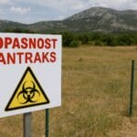 Antraks u Hrvatskoj, Znak upozorenja na antraks ispred ograđenog pašnjaka u Dalmatinskoj zagori, uz planinski pejzaž u pozadini.