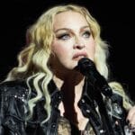 Madonna na pozornici u crnoj kožnoj jakni i s akustičnom gitarom